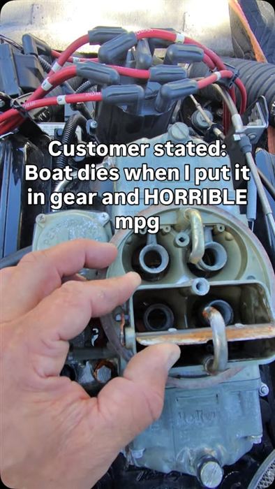 A Holley carburetor held open during a diagnosis, worn throttle plates visible.