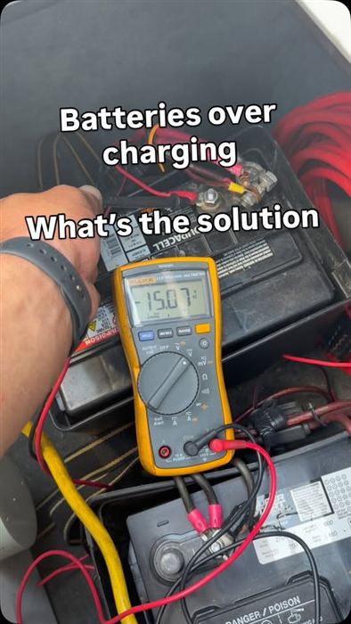 A Fluke multimeter reading 15.07 volts across marine batteries during a charging-system test.